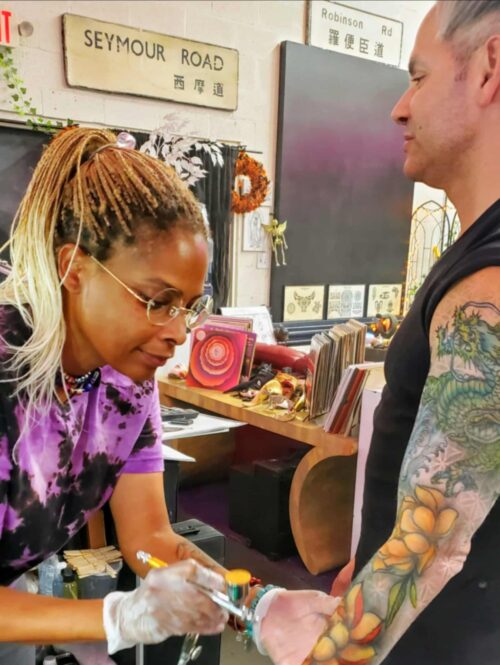 Grace X Lovejoy applying an airbrush tattoo sleeve